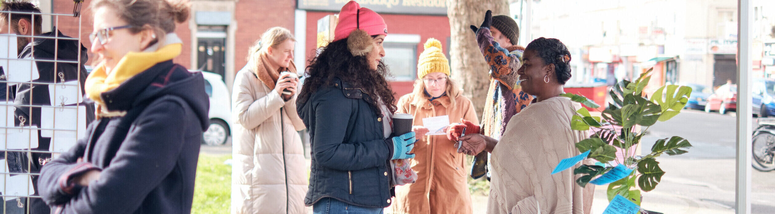 An on street consultation, people under a gazebo having conversations with multiple activites around them